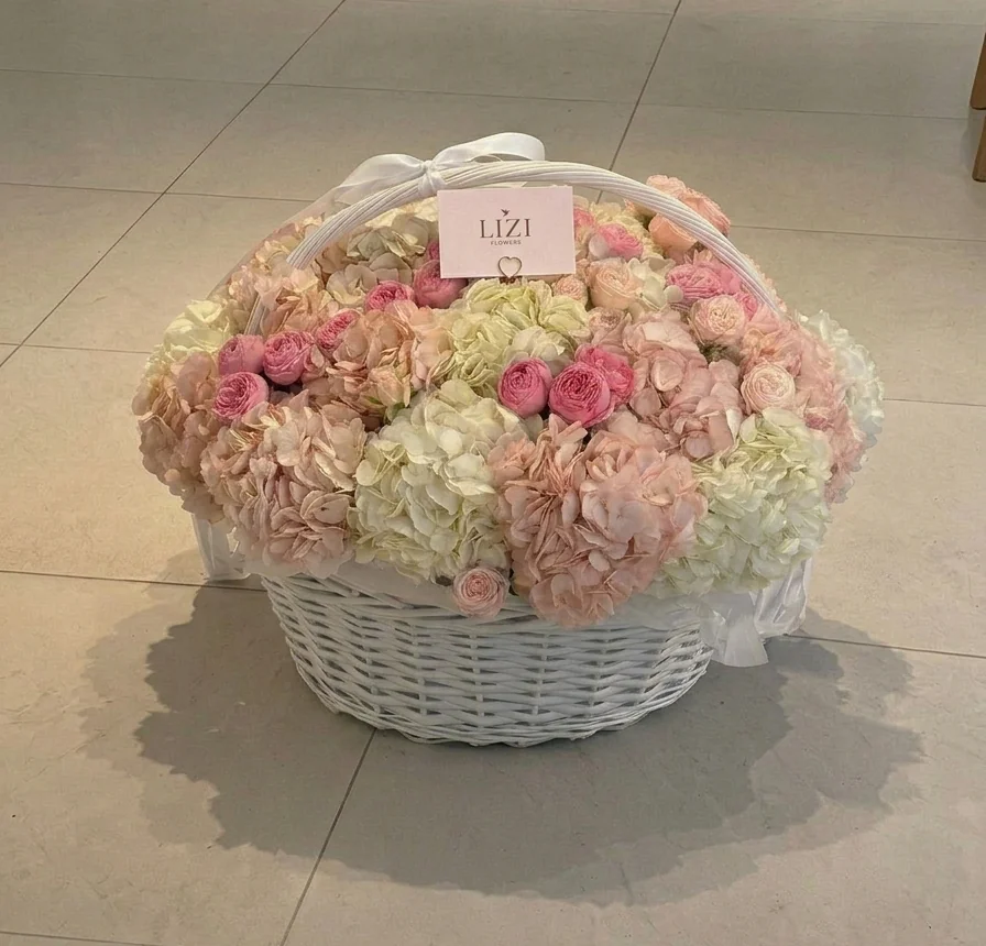 Canasta de mimbre blanco con hortensias y rosas en tonos pastel