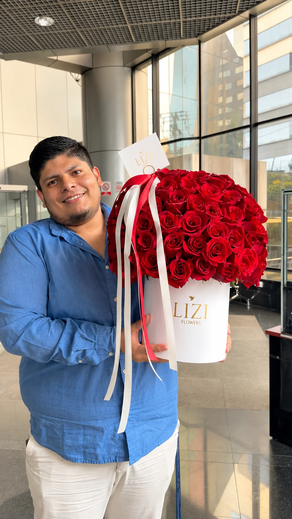 Cliente con un arreglo cilíndrico de rosas rojas