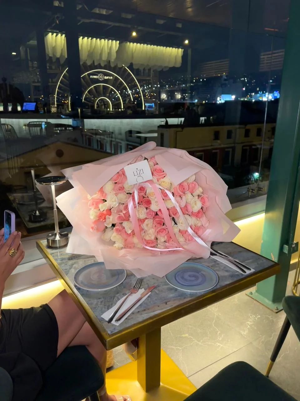 Bouquet de flores rosadas sobre una mesa junto a la ventana